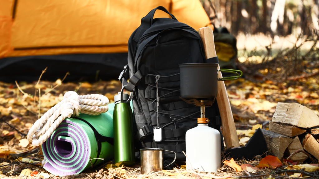 A camping setup featuring a backpack, water bottle, and various supplies arranged on a surface.