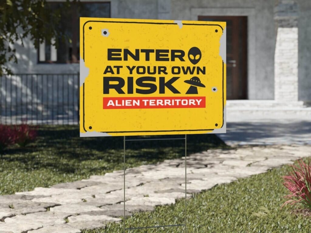 Custom garden sign in yellow with an “Enter at your own risk. Alien territory” print.