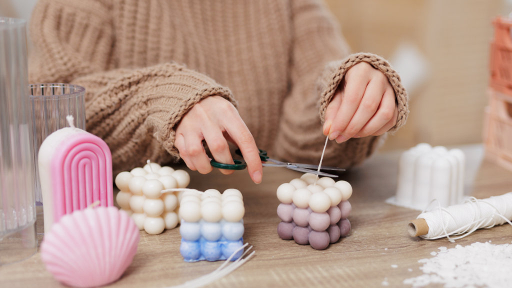 A woman making custom candles in various shapes, sizes, and colors.