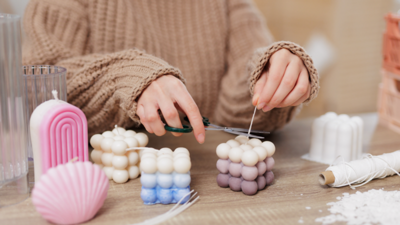 A woman making custom candles in various shapes, sizes, and colors.