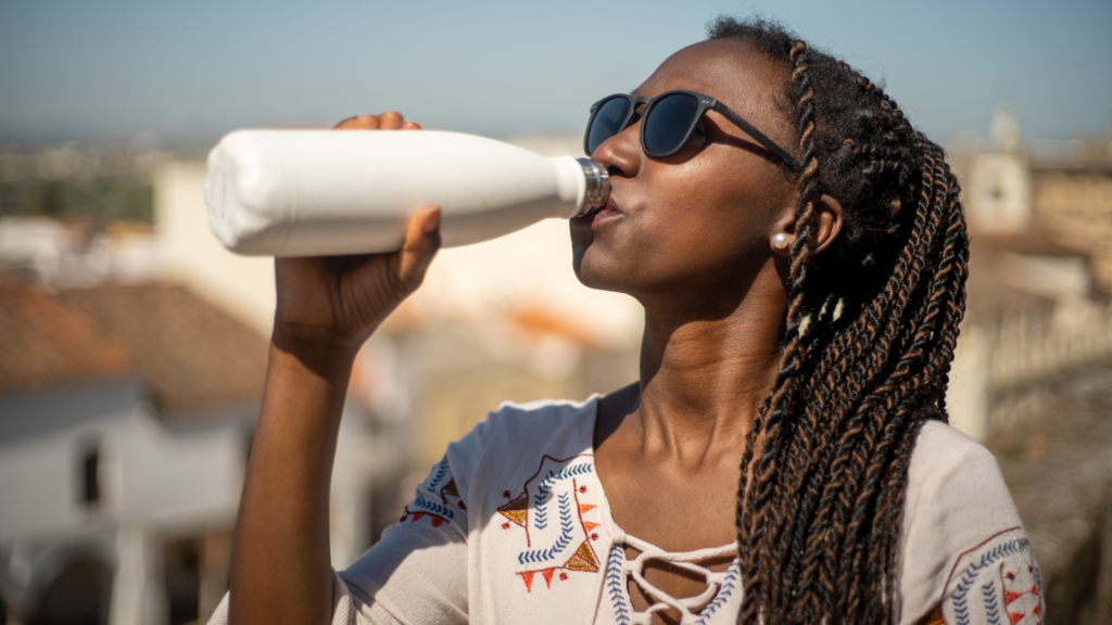 A woman takes a drink from a bottle, appearing relaxed and content.