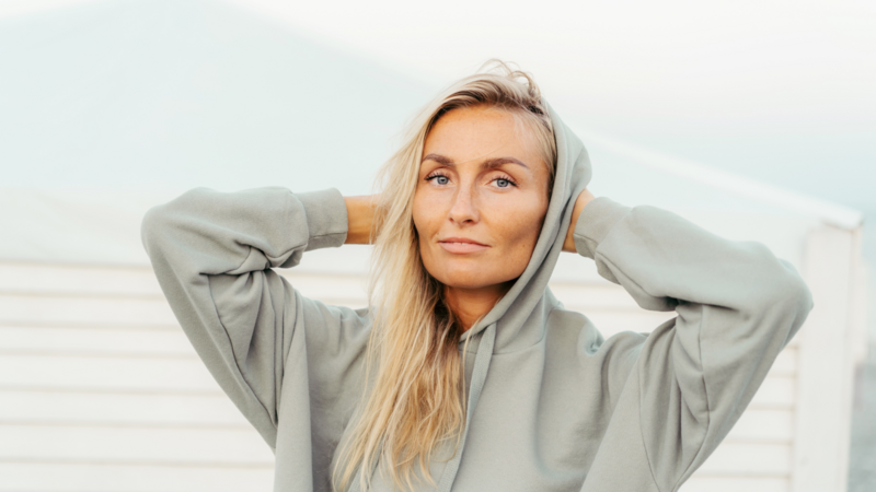 A woman wearing a grey hoodie showcasing a casual yet stylish outfit.