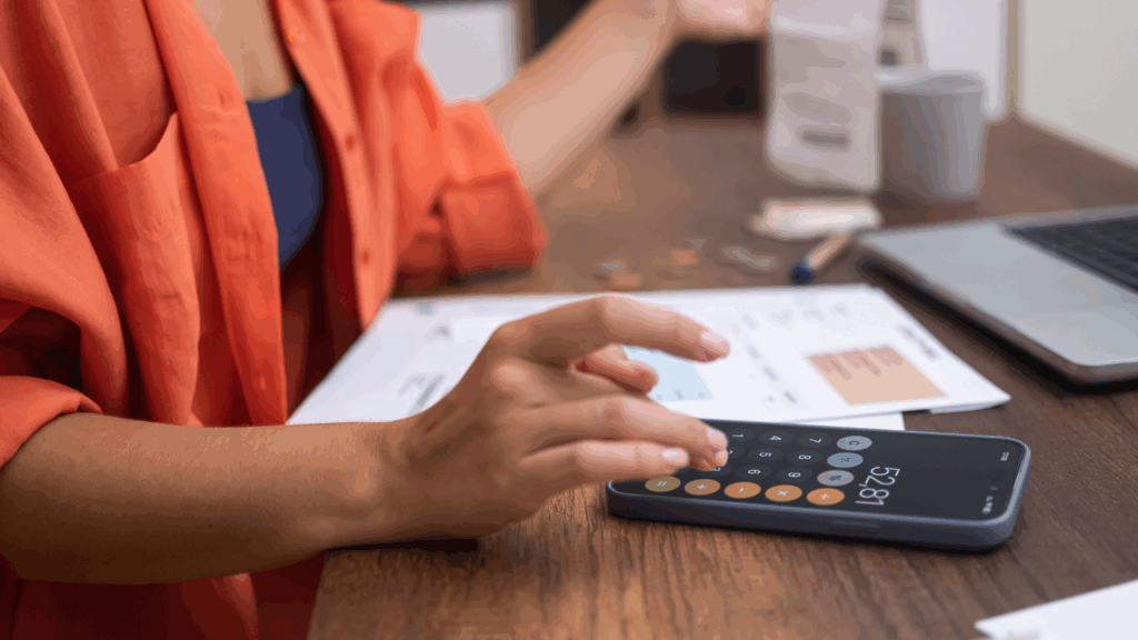 A woman using a mobile phone to perform calculations.