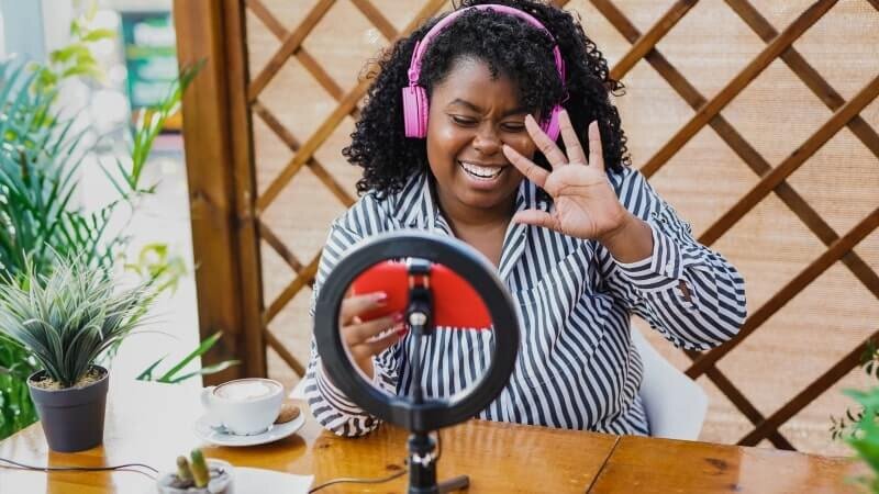 A woman making TikTok videos while wearing headphones.