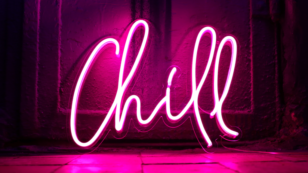A bright pink neon sign spells "Chill" in cursive against a dark wall.