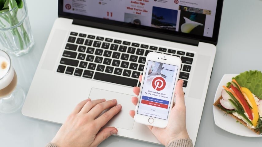 A woman holding a mobile phone with Pinterest open.
