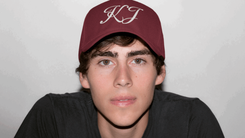 A young man wearing a maroon hat featuring the letters prominently displayed on the front.