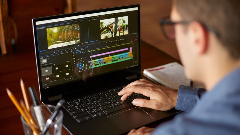 A person editing video on a laptop with software open, showing a timeline and video clips.