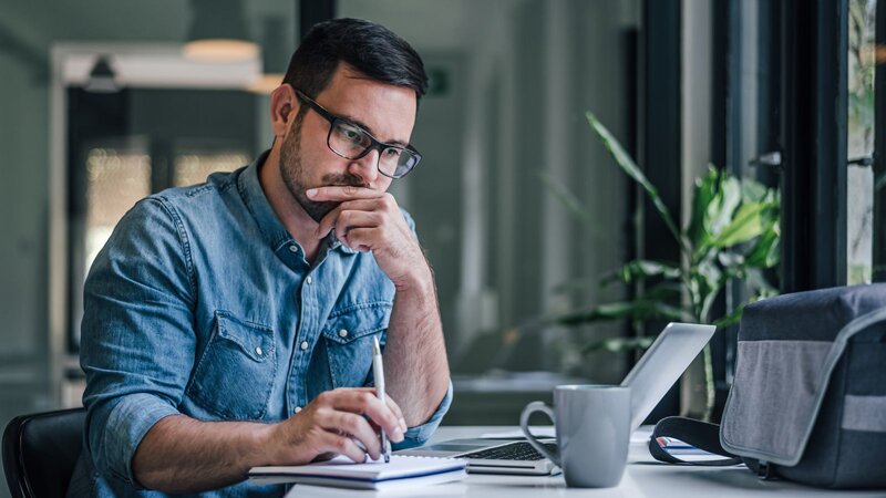 A man is working on a laptop and thinking