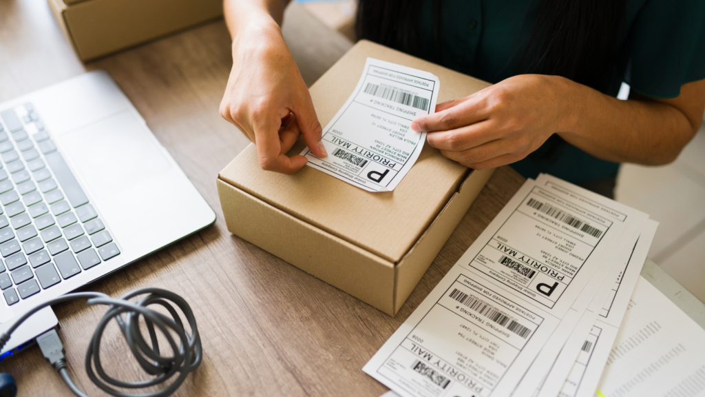 A person sticking a shipping label on top of a cardboard box.