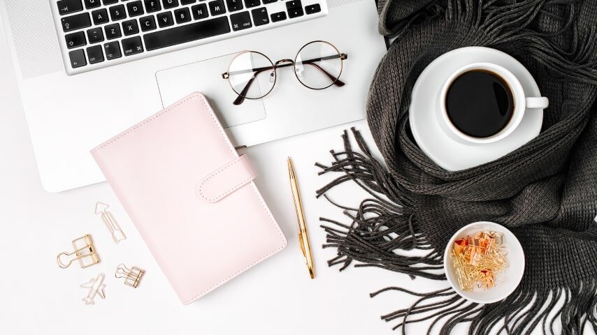 A pink planner notebook placed on top of a laptop.