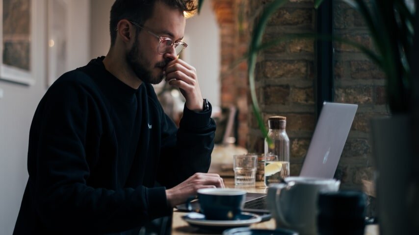 A man with the glasses sitting in front of a laptop.