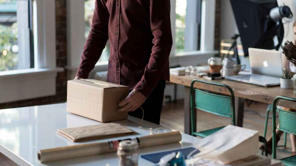 A man preparing a delivery box for shipment.