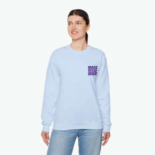 A woman wearing a light blue hoodie with a small abstract shape print against a white background.