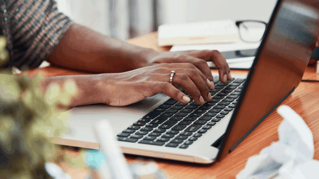A person typing on a laptop keyboard.