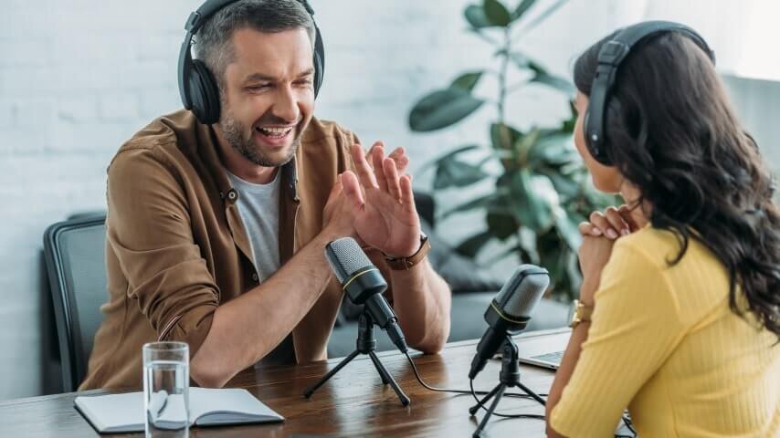A man and a woman recording a podcast in a studio.