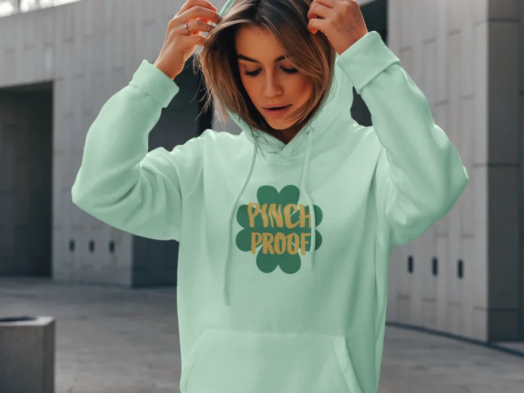 A woman in a mint green hoodie with a St. Patrick’s Day-themed “Pinch Proof” print on the front.