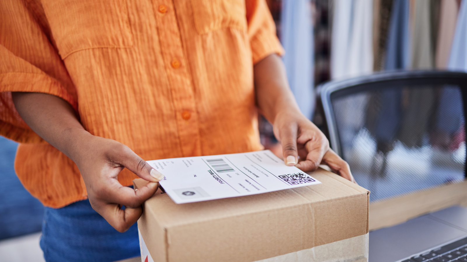 A person sticking a delivery sticker on top of a box.