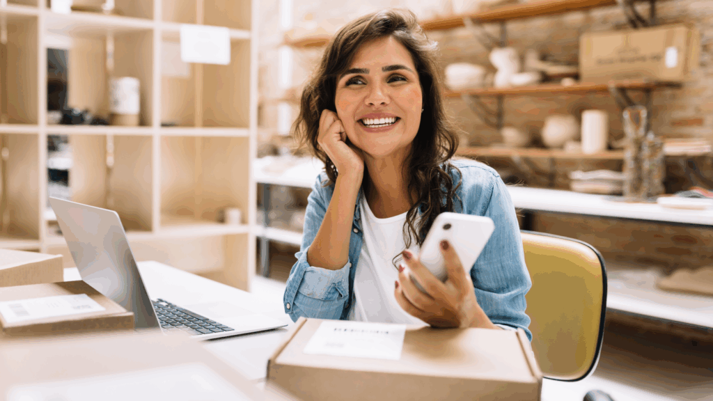 A smiling woman is using a mobile phone to do dropshipping as a side business idea.