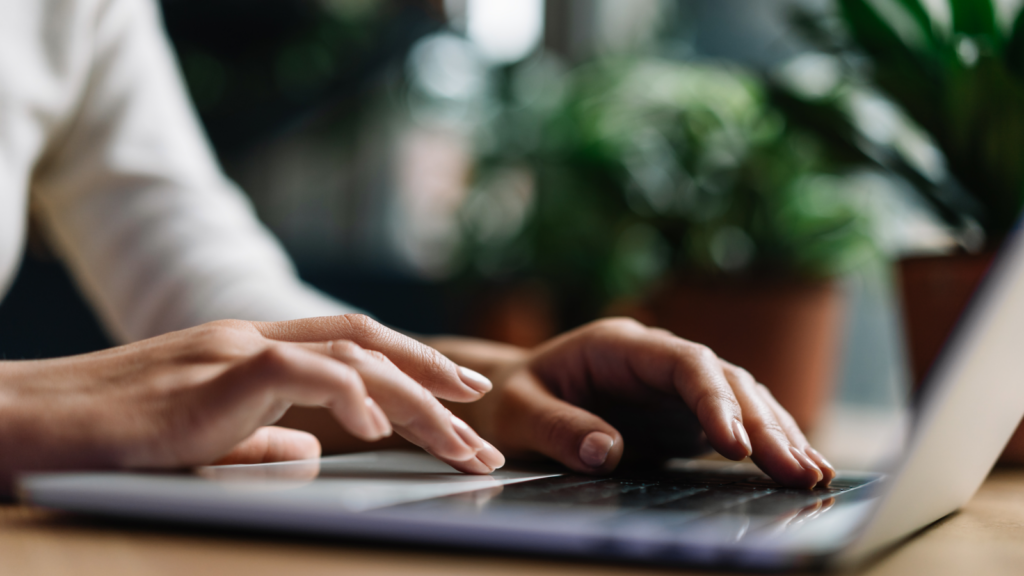 A woman typing on a laptop keyboard and searching how to make $1,000 a week.