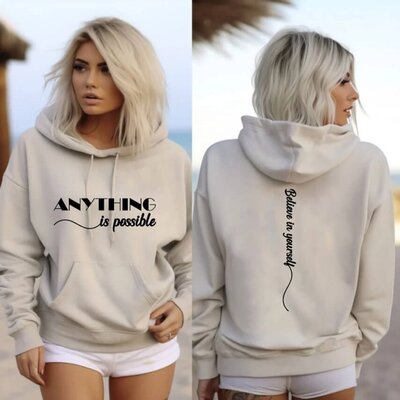 A woman wearing a sand-colored hoodie that says "Anything is possible, believe in yourself."