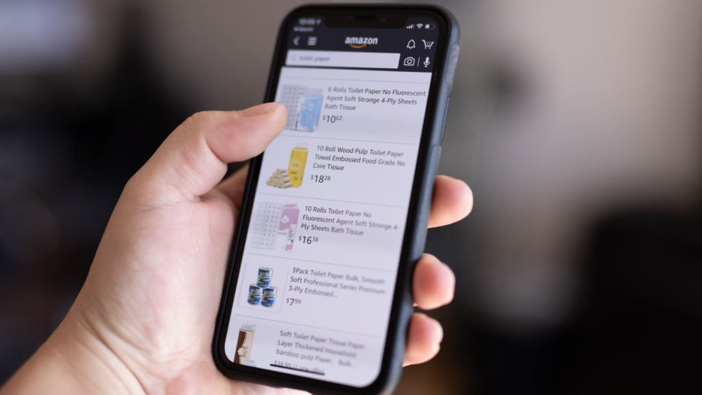 A mobile phone held in hand with Amazon’s search page on the screen.
