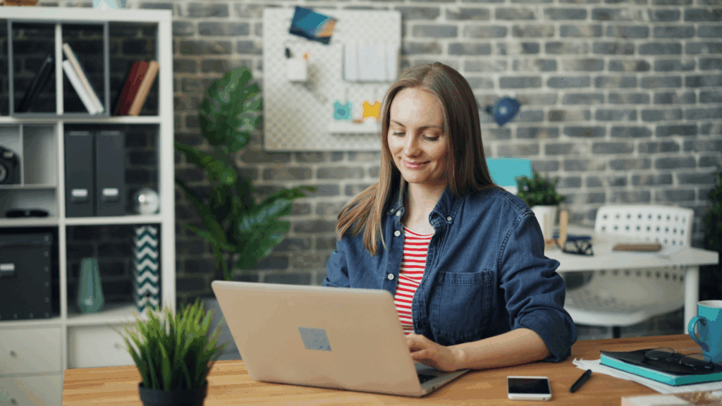 A woman is sitting at a desk and using a laptop to analyze TikTok ad performance.