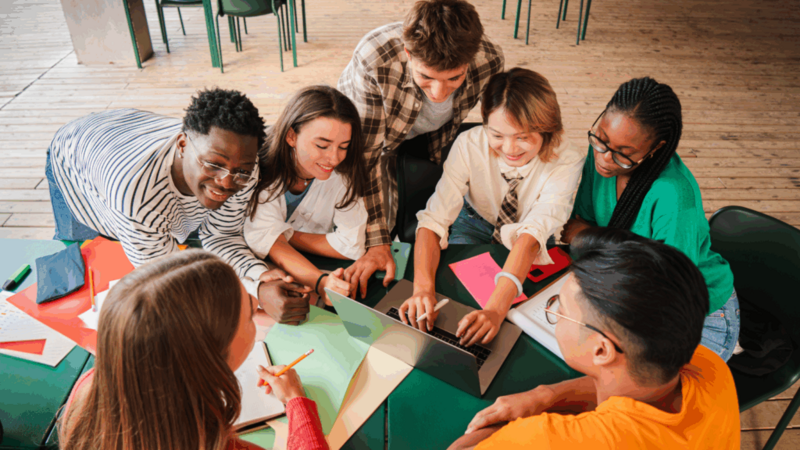 A group of young people around a table, debating on the best business ideas for teens.