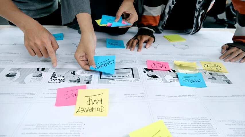 People putting sticky notes on a board.