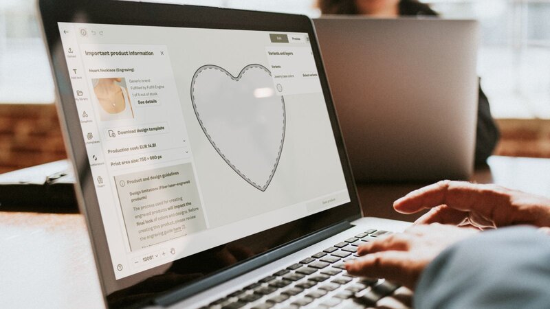 A person is using a laptop to design a custom necklace using Printify’s Product Creator.