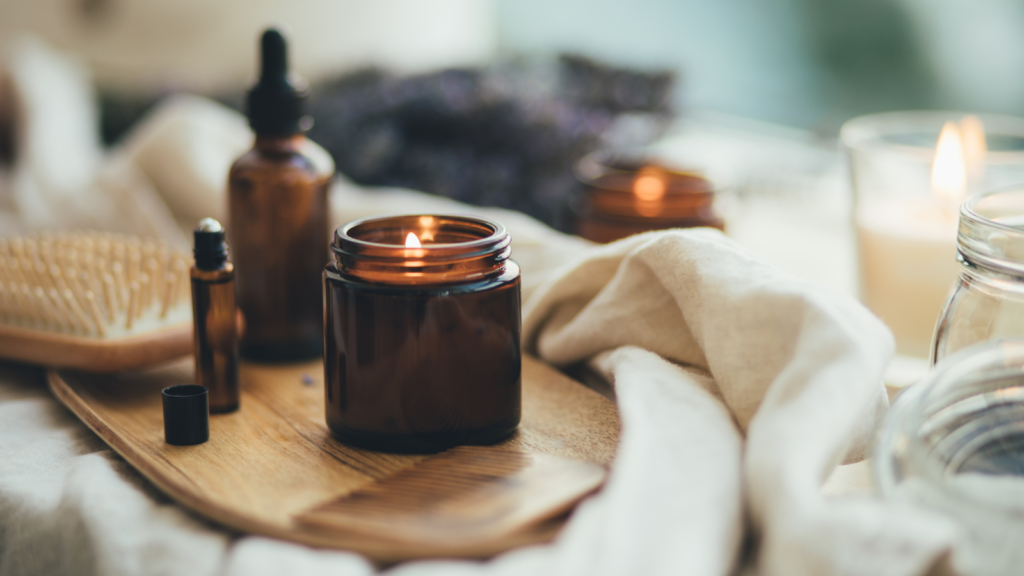 A wooden tray displaying various candles and essential oils, creating a serene and aromatic ambiance.
