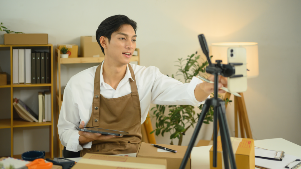 A man recording himself with a mobile phone while marketing dropshipping products from his Shopify store.