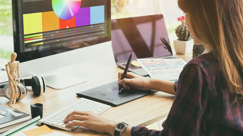 A woman focused on her computer, analyzing a color wheel for design purposes.