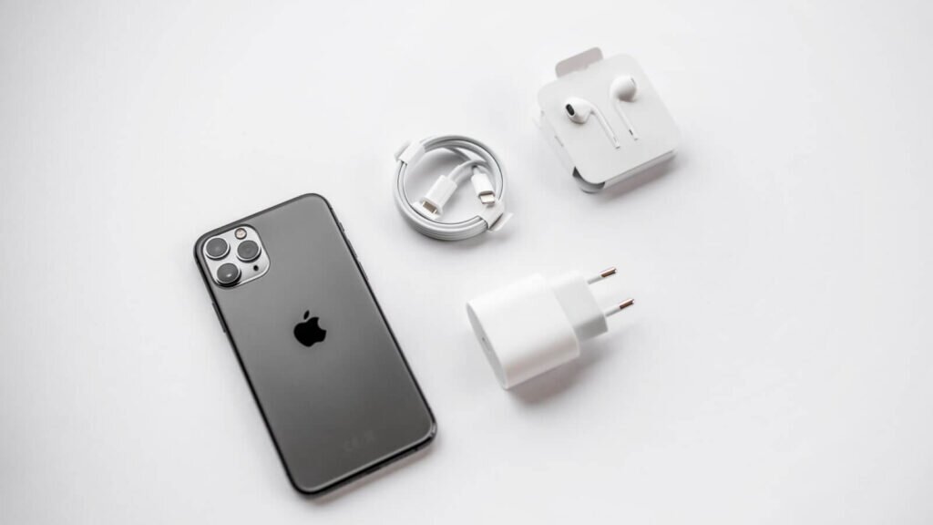 An iPhone next to its charger and headphones.