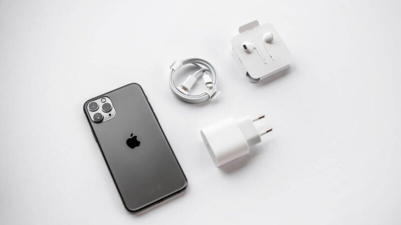 An iPhone next to its charger and headphones.