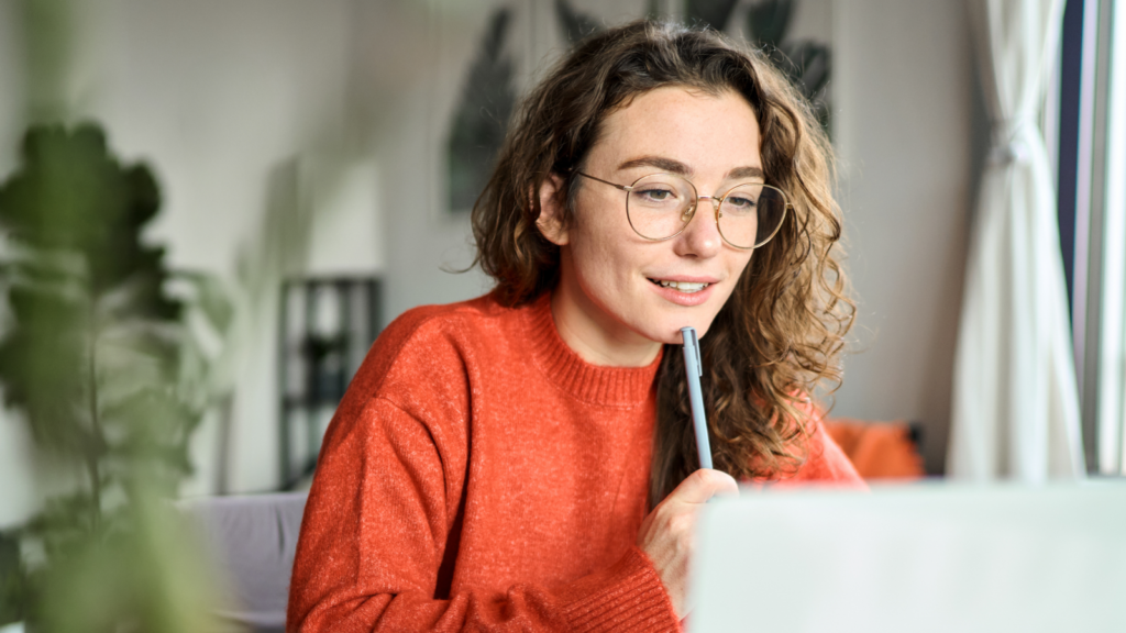 A woman wearing glasses is focused on her laptop screen, engaged in work or research.