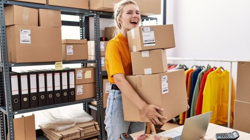 A woman holding a pile of closed and labeled packages for her eCommerce business.