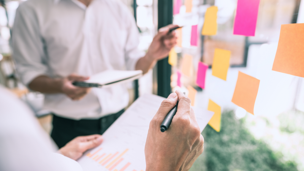 Team members engaged in project planning, using sticky notes for brainstorming ideas in a modern office setting.