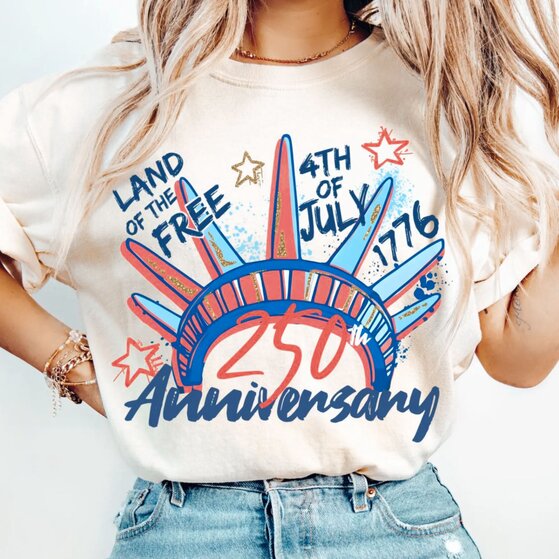 A woman posing in a beige patriotic 4th of July t-shirt that says 
