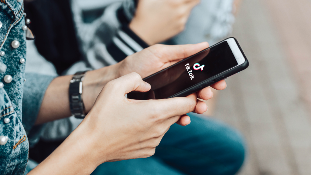 Two people holding smartphones, focusing on one with the TikTok app open.