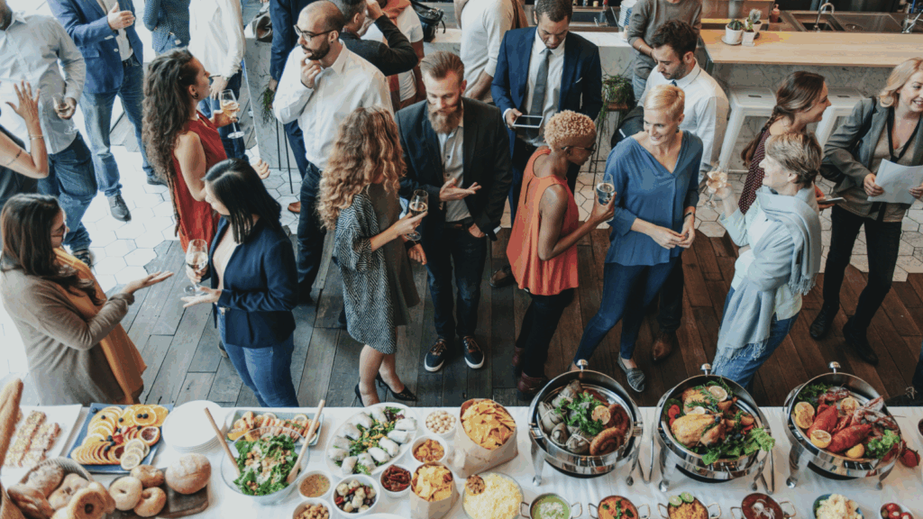 A group of people gathered around a buffet table filled with various dishes and food items.