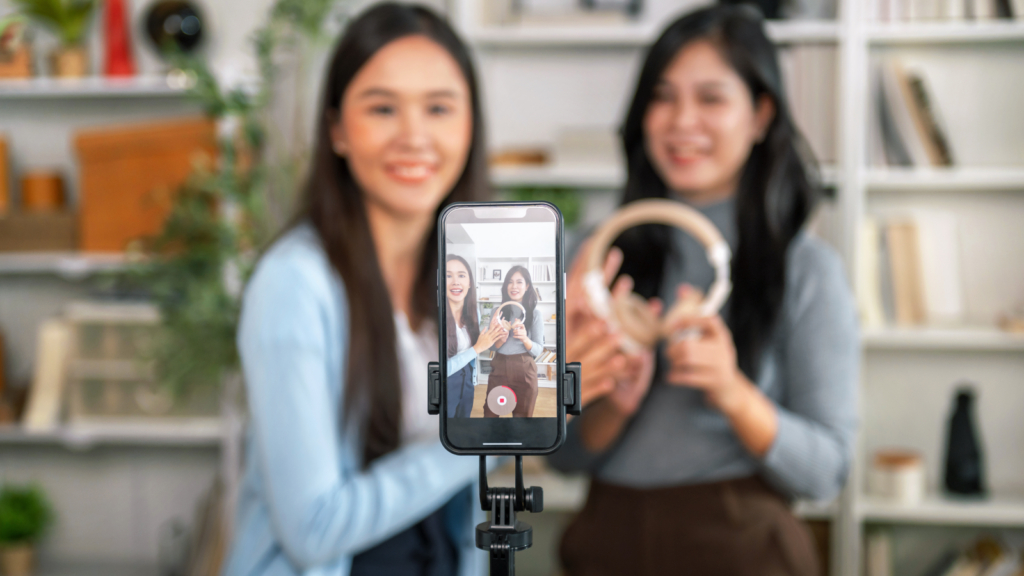 Two women recording themselves using a mobile phone.