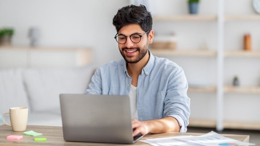 A man looking at a laptop screen and smiling.