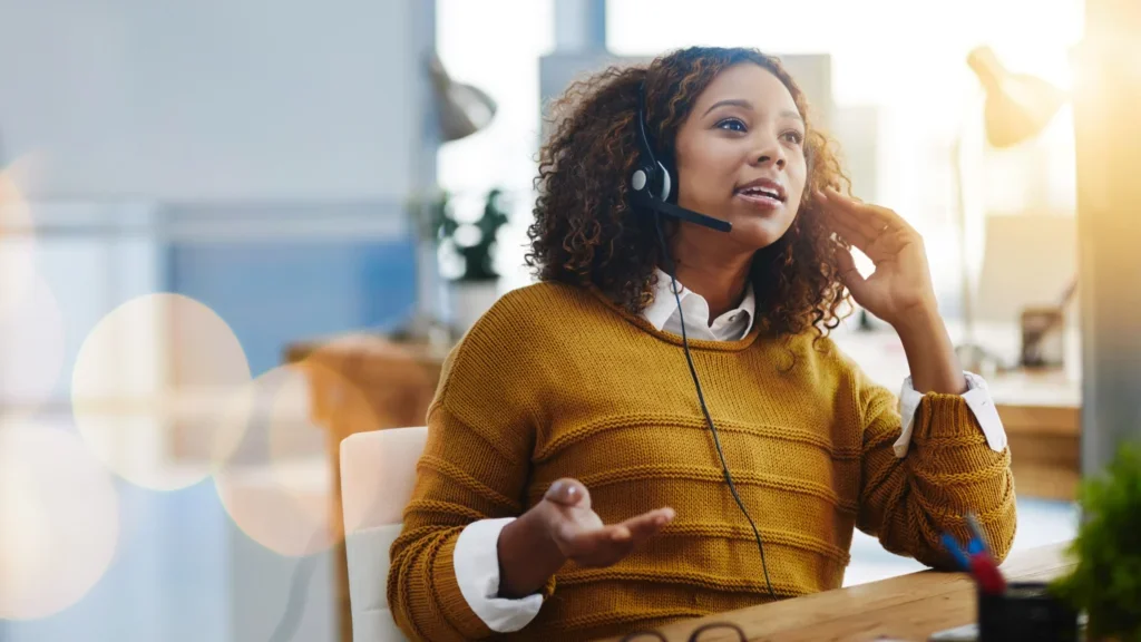 A woman with a headset is seated at a desk, focused on virtual assistant work.