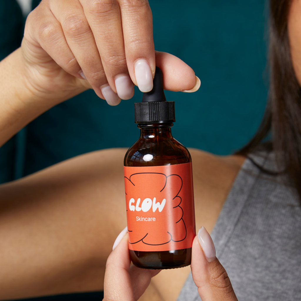 A “Glow” skincare product bottle held in hands.