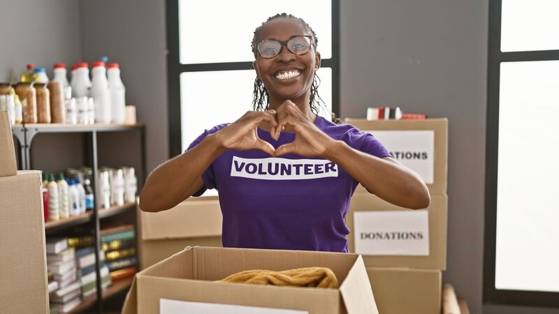 A volunteer is showing a heart sign with their hands