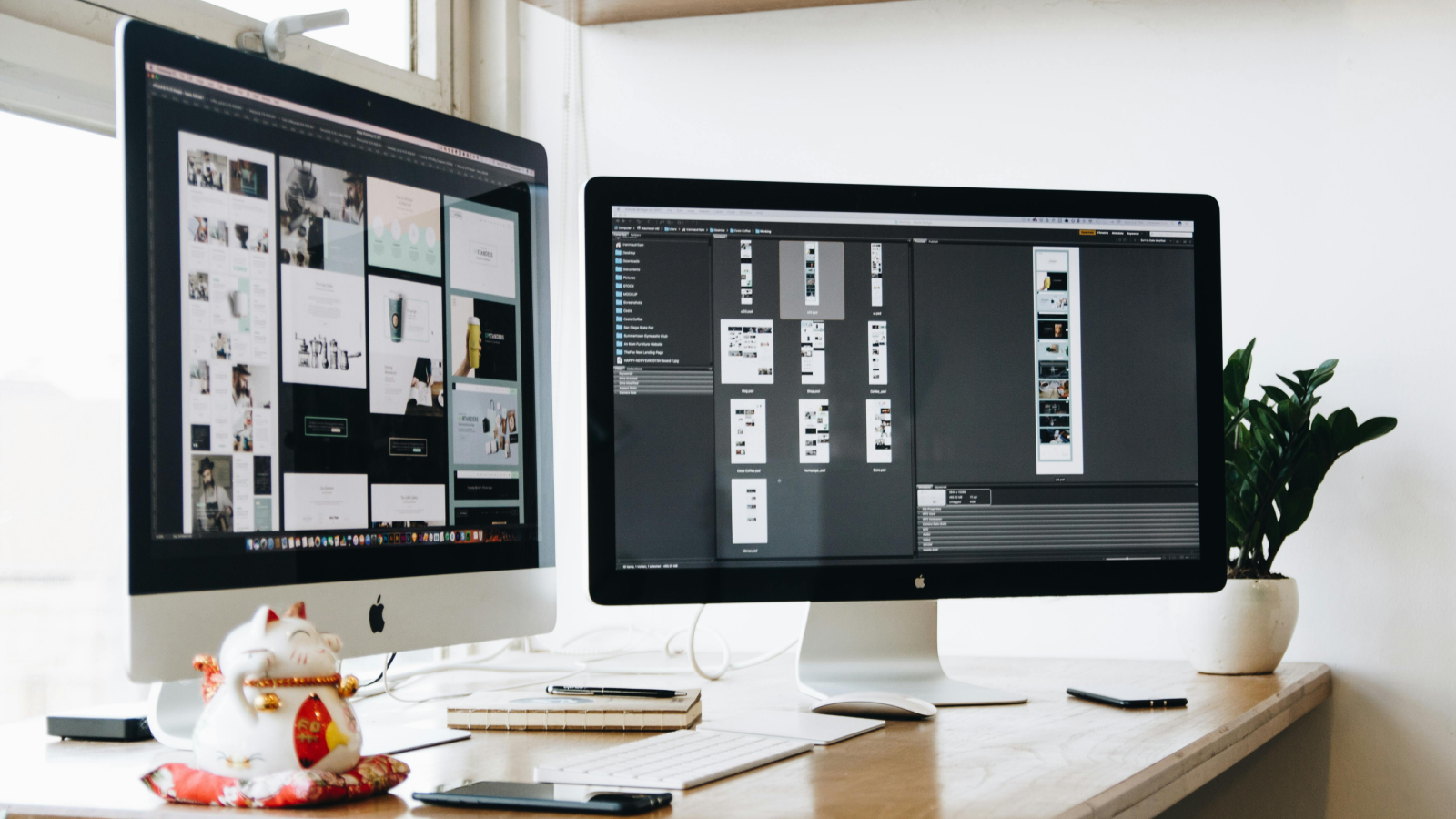 Two monitors standing on top of a desk with various branding design assets on the screens.
