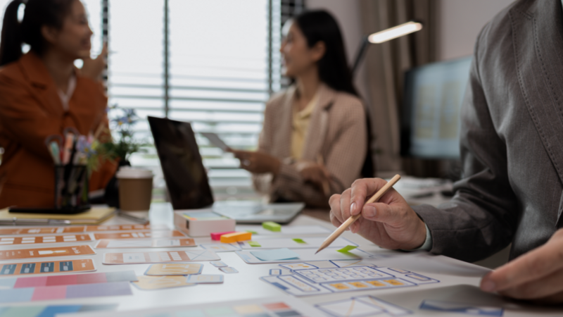 A person collaborates with colleagues on a design project, showcasing teamwork and creativity in a professional setting.
