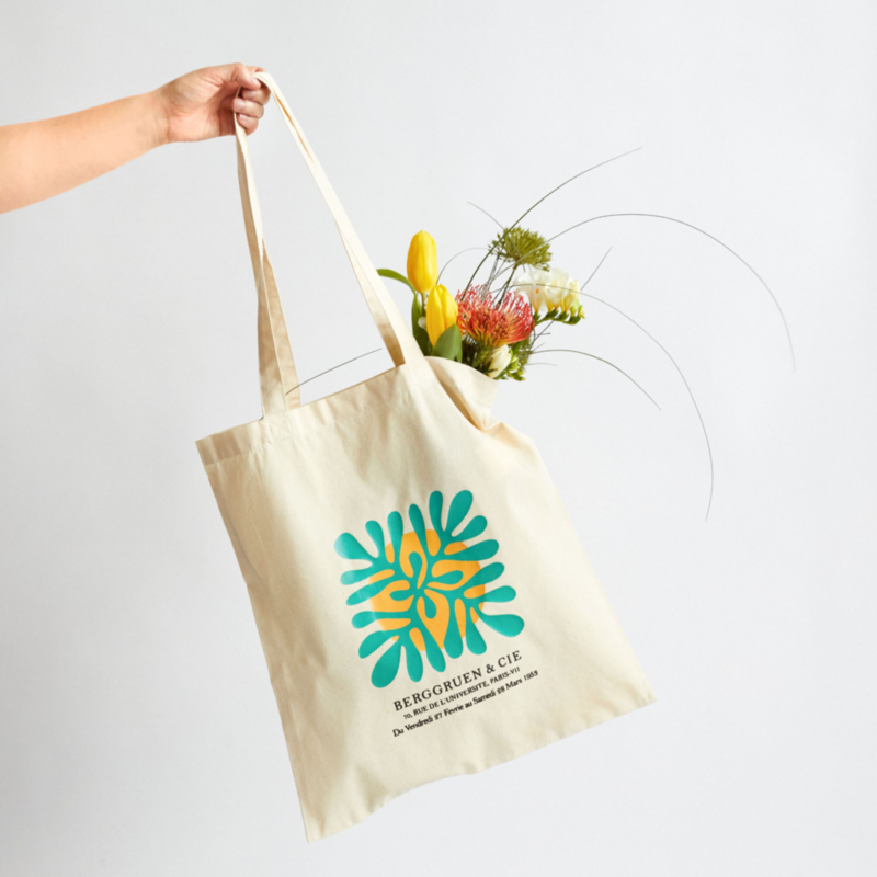 A hand is seen holding a floral tote bag.