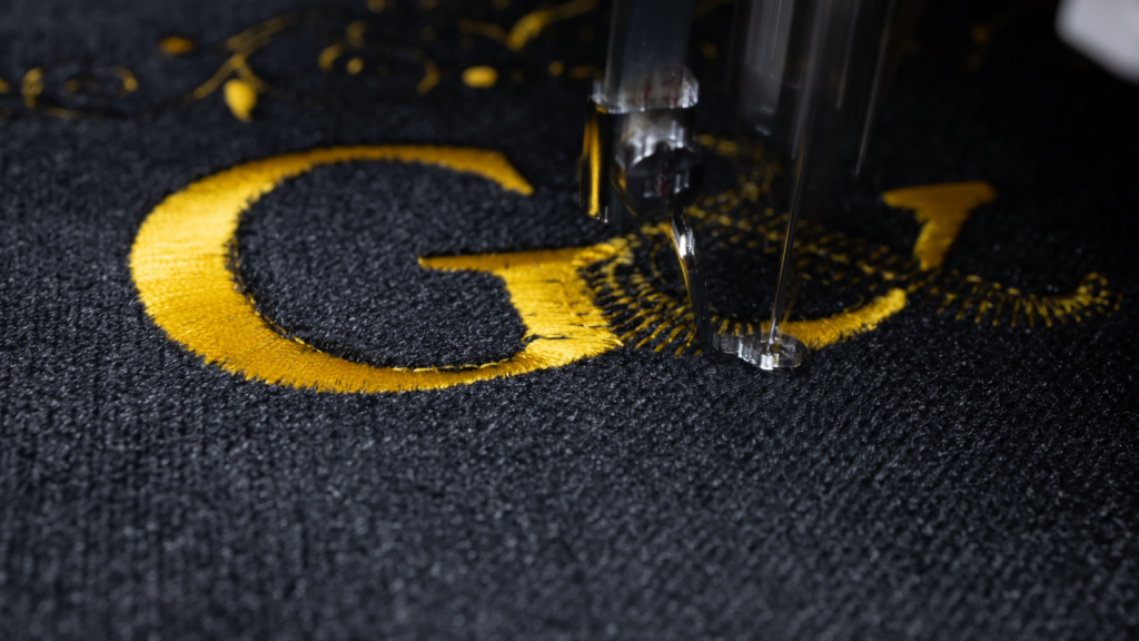 Close-up of a sewing machine featuring the embroidered letters "G&" prominently displayed on the fabric.